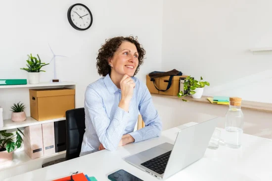 Smiling woman sitting at an office desk with a laptop.