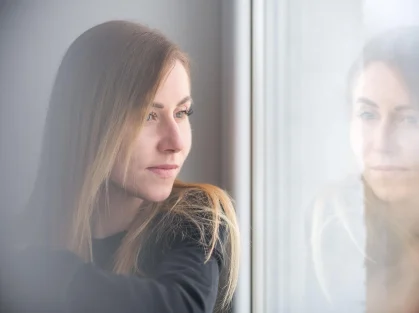 Woman looking out of a window in soft light.
