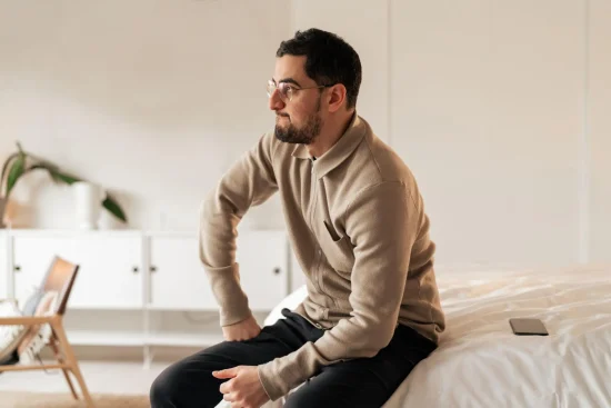 Man sitting indoors looking to the side thoughtfully.