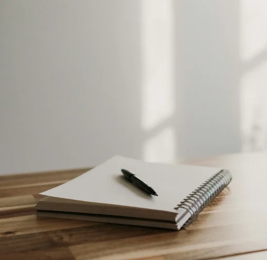 Notebook and pen on a desk in sunlight.