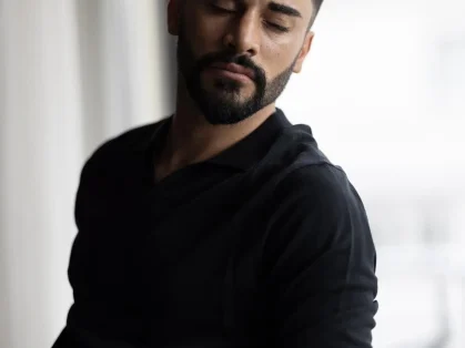 Man in a black sweater looking down thoughtfully.